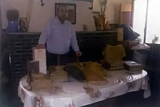 Un hombre de pie junto a una mesa con libros parroquiales antiguos dispuestos para su reproducción.