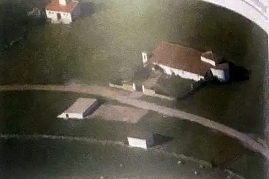 Vista aérea de la Ermita de la Jara: edificio blanco con tejado de teja junto a un camino de tierra.