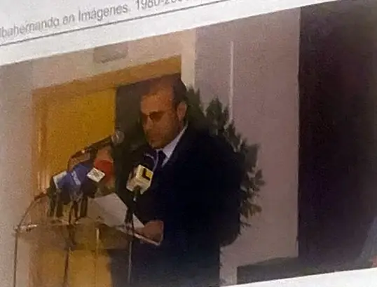 Un hombre de traje habla ante un atril con varios micrófonos de medios de comunicación.