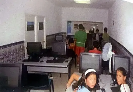 Niños y niñas sentados ante ordenadores en el aula de la asociación.