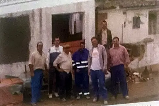 Siete hombres con ropa de trabajo posan ante la fachada encalada de la sede durante las obras.